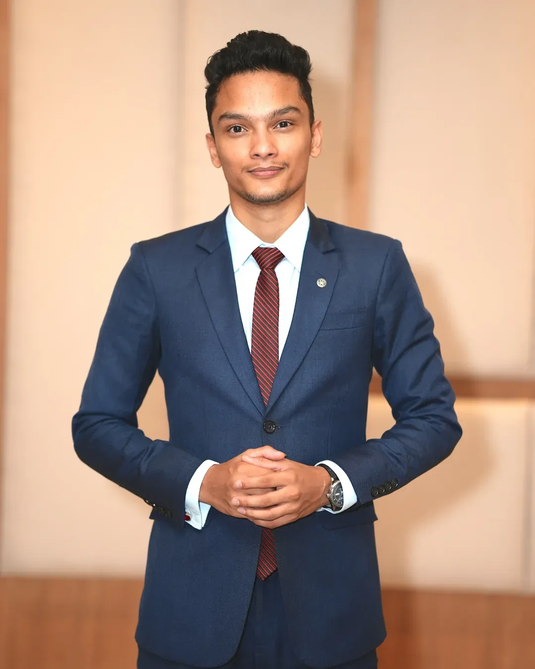 Kovid Panthy standing in a navy suit and striped tie, hands clasped.