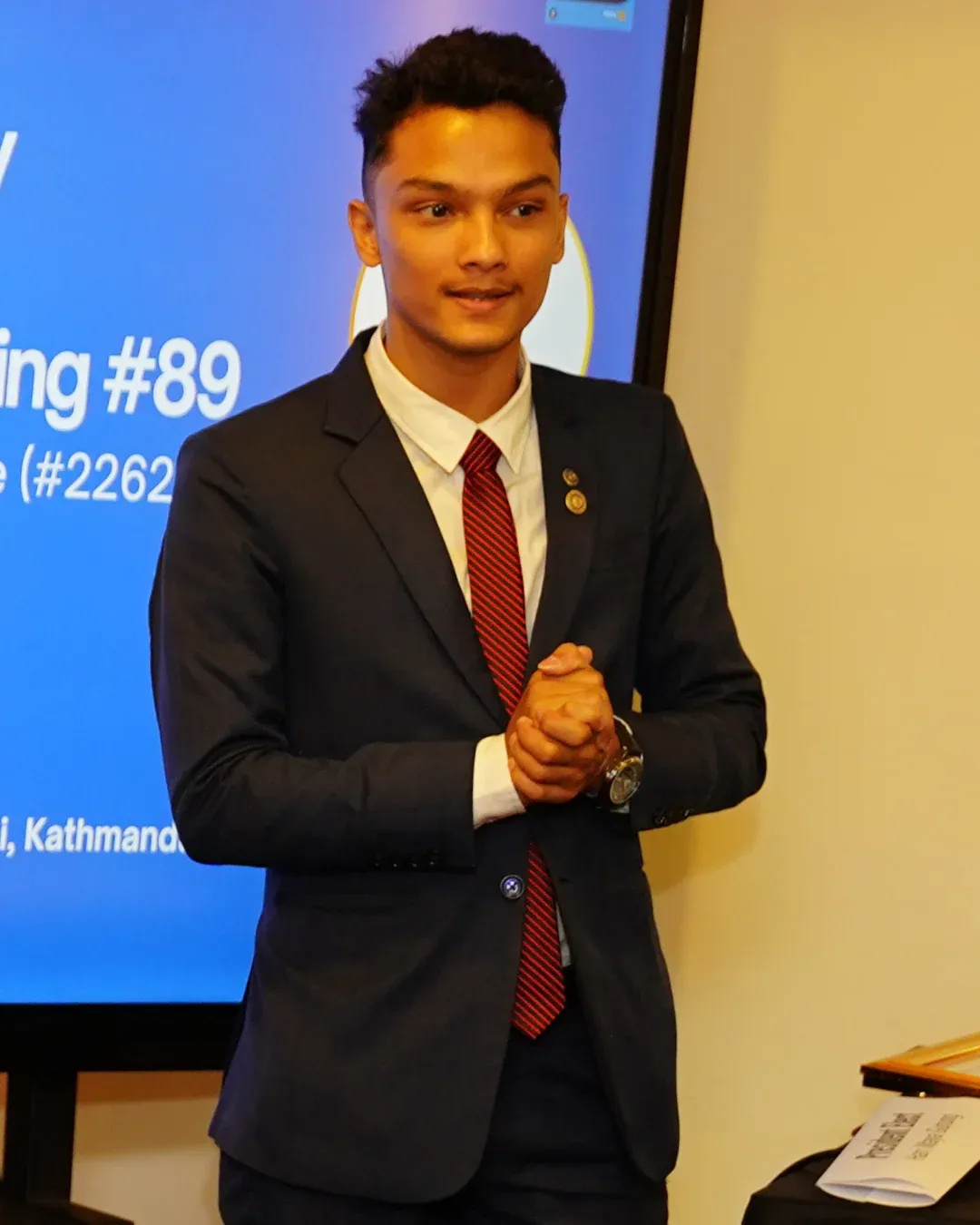 Kovid Panthy addressing a room, a projected slide behind him.