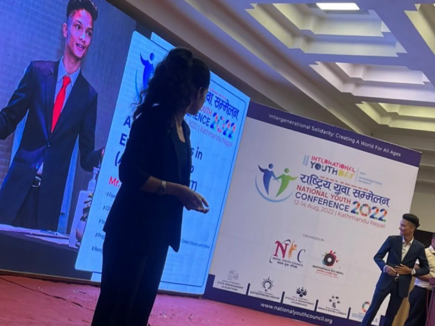 The National Youth Conference 2022 hall, Kovid Panthy at the side of the stage and his slide projected on the screen.