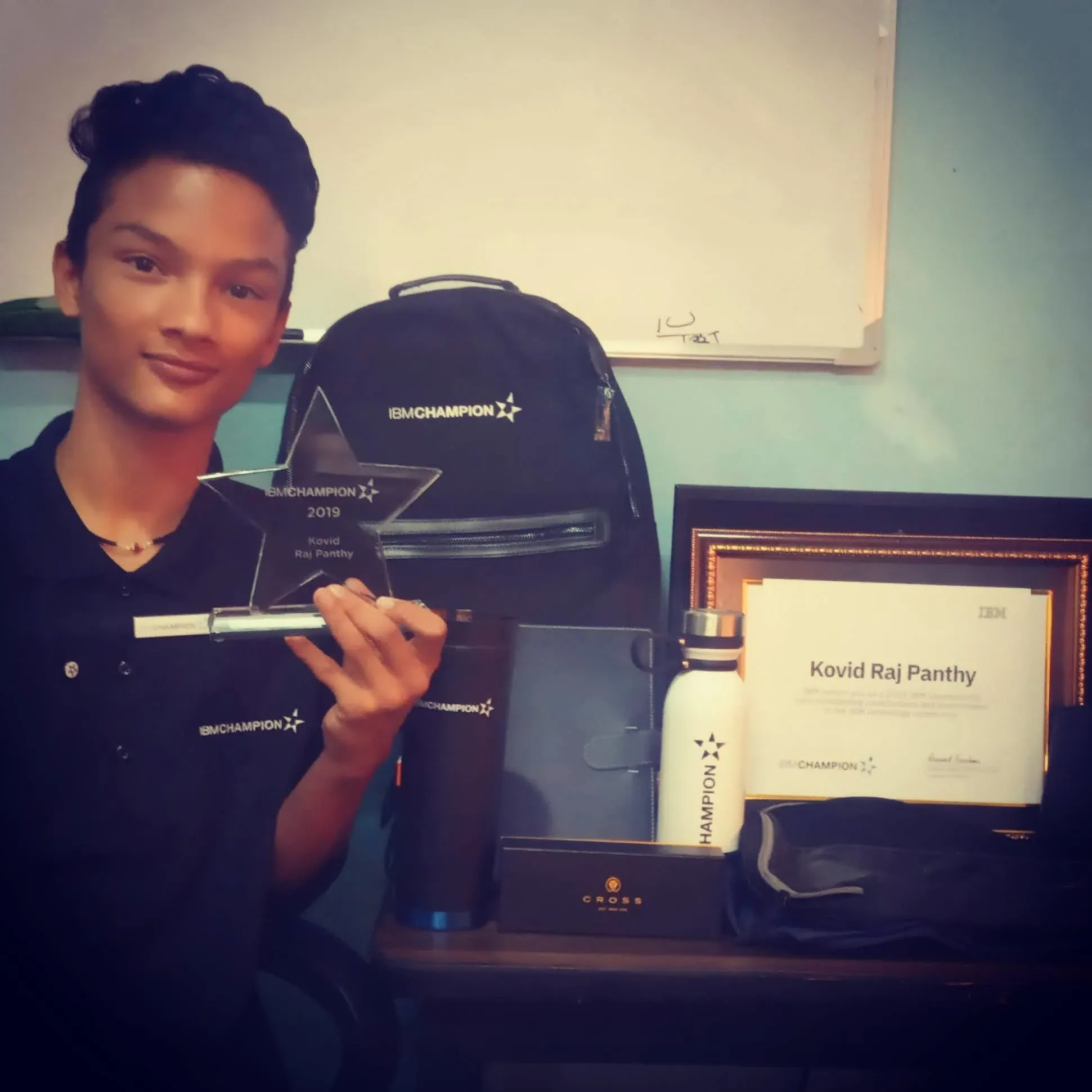 Kovid Panthy holding the star-shaped IBM Champion 2019 award engraved with his name, beside the certificate and kit.