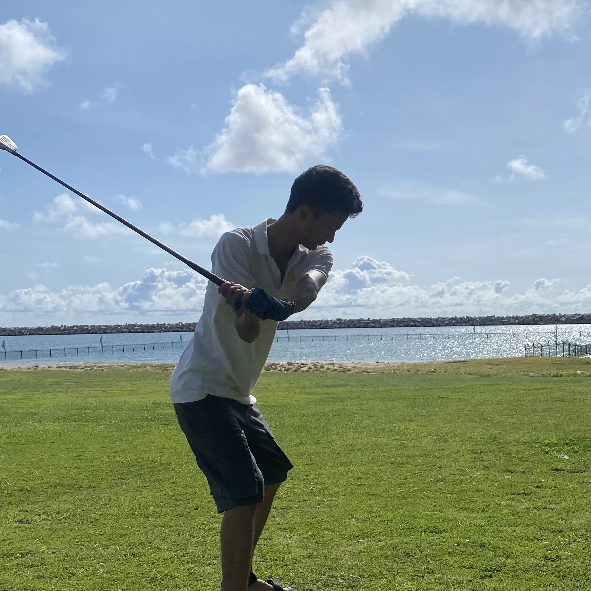 Kovid Panthy mid-swing on a course beside open water.