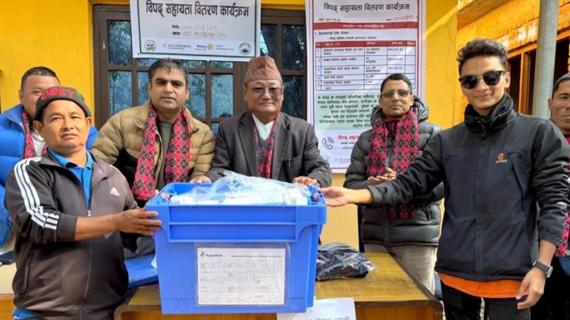 Kovid Panthy with others behind a table of relief crates at a disaster relief distribution programme in Mandandeupar.