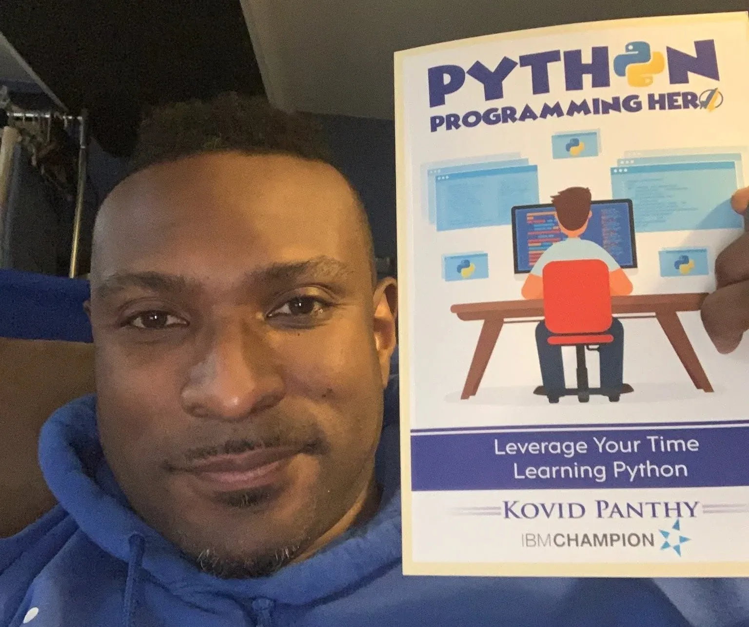 A reader holding a copy of Python Programming Hero, the cover crediting Kovid Panthy, IBM Champion.