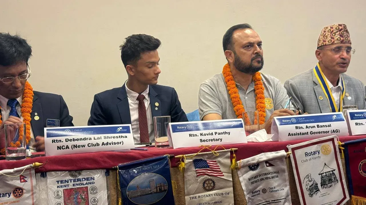 Kovid Panthy seated at a Rotary head table behind a nameplate reading “Rtn. Kovid Panthy, Secretary”, club banners along the front.