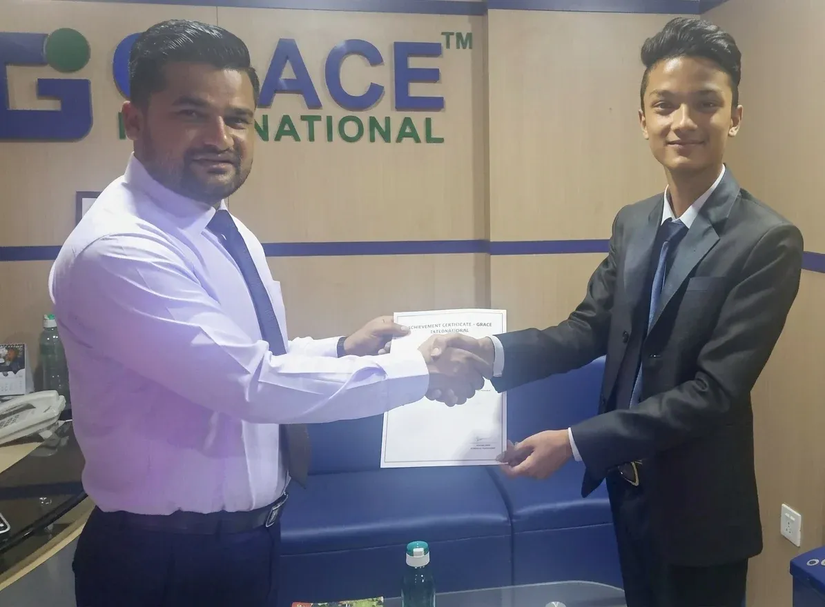 Kovid Panthy shaking hands and holding a certificate at the Grace International offices.